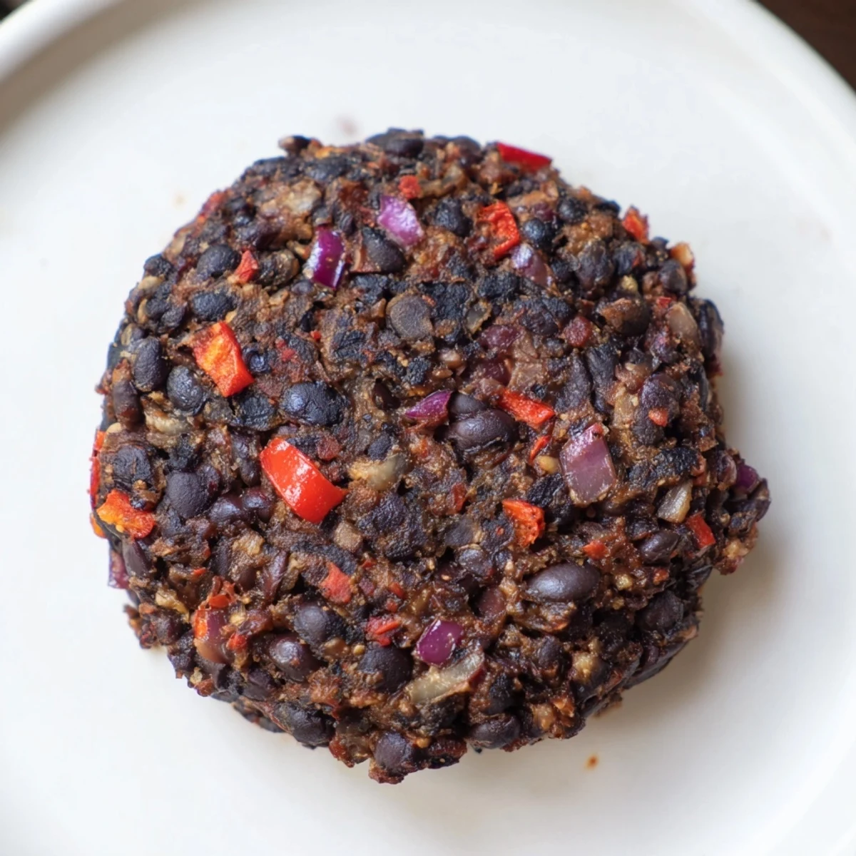 Golden-brown vegetarian black bean burgers sizzling in a pan, full of vegetable and spice flavors.
