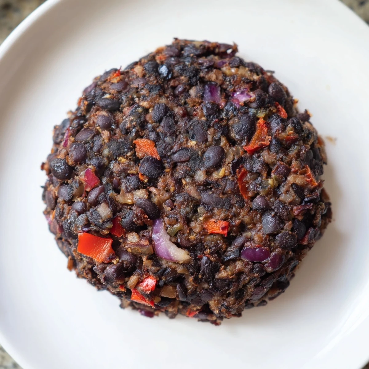 Stacking a juicy vegetarian black bean burger with fresh tomato, a perfect vegetarian meal option.