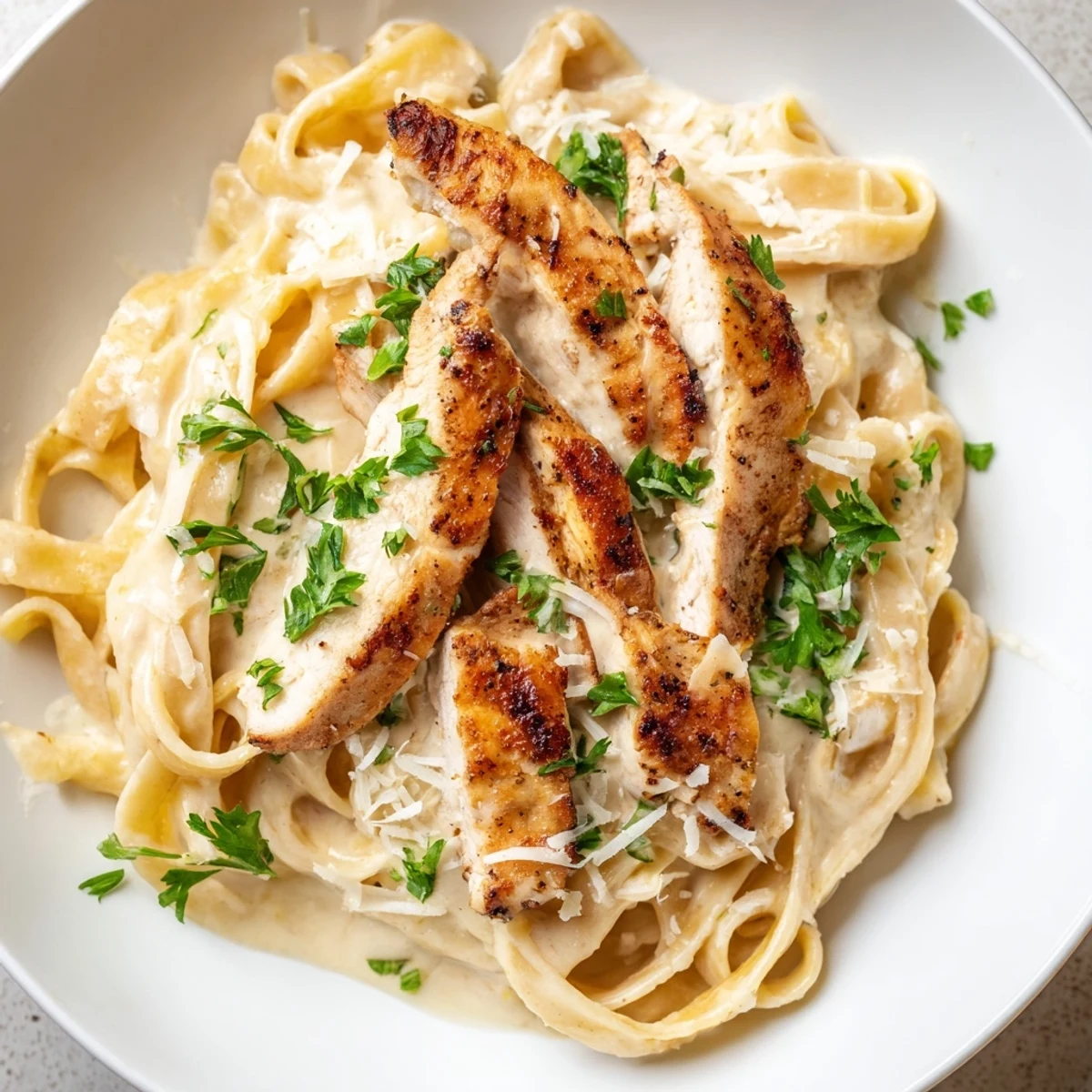 Creamy Cajun Chicken Alfredo with tender pasta strips and rich, spicy sauce, garnished with fresh parsley and Parmesan.