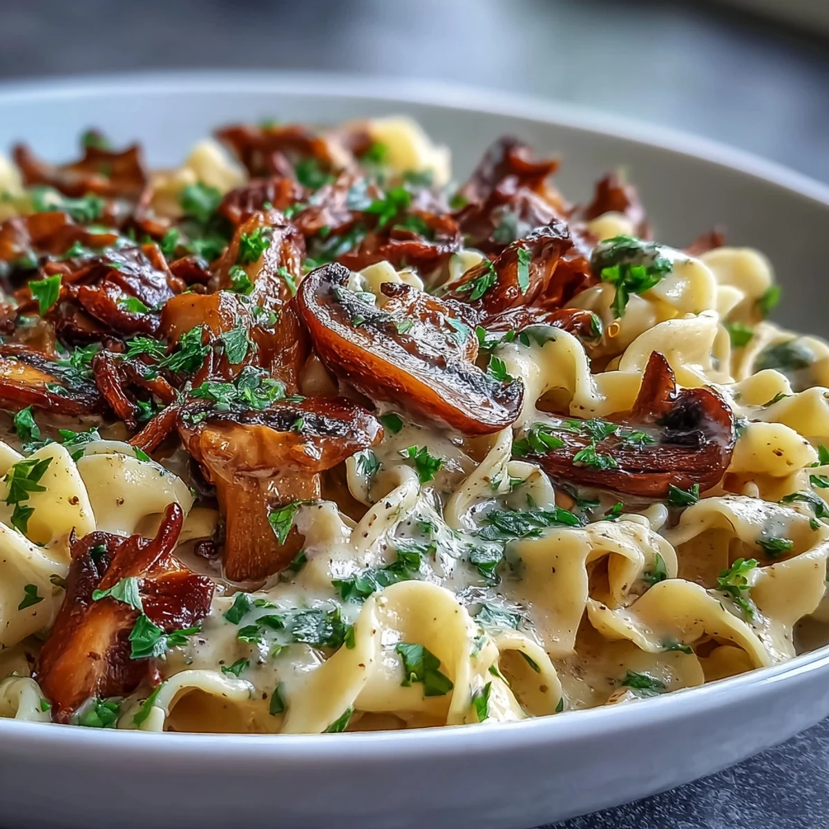 Close-up of Creamy Mushroom Stroganoff featuring glossy, umami-rich sauce coating silky noodles, paired with a crisp white wine for an elegant serving suggestion.