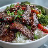 Tender beef slices glazed in homemade teriyaki sauce, served over white rice with sautéed veggies.