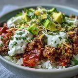 A colorful Turkey Taco Bowl with seasoned turkey, fluffy rice, crisp lettuce, and creamy avocado, ready to serve with lime wedges.
