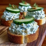 Showcasing elegant Derby Day Benedictine Cucumber Canapés with fresh dill garnish.