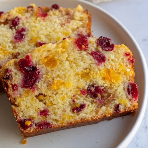 Close-up of a freshly baked seasonal cranberry and orange bread loaf, dusted with sugar.