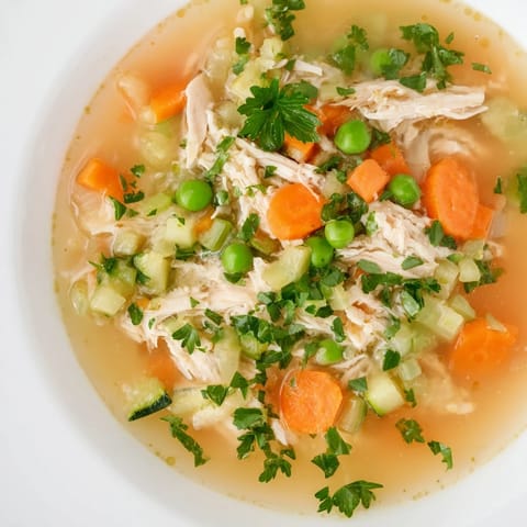 Fresh Spring Garden Chicken Soup garnished with parsley, showcasing zucchini slices and shredded chicken floating in a savory aromatic broth.