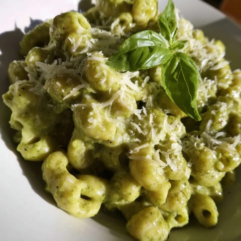 Luscious green avocado pesto sauce coating macaroni noodles, highlighting a vegetarian and gluten-free dinner option.