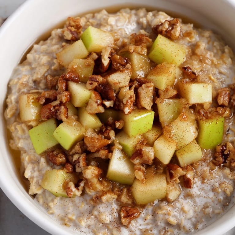 A comforting photo of a warm, cinnamon-infused apple pie oatmeal bowl served in a light-colored bowl.