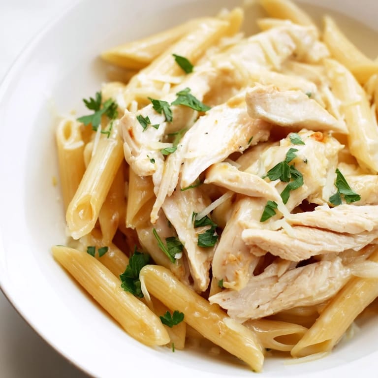 A close-up of Roasted Garlic Chicken Penne in a skillet, steam rising from the rich, cheesy Italian-American pasta dish.