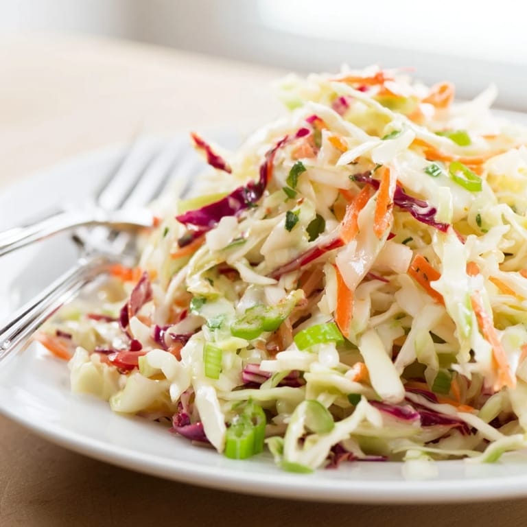 A fresh Best Cabbage Coleslaw tossed in a tangy dressing, perfect alongside grilled barbecue sandwiches at an outdoor summer picnic.  